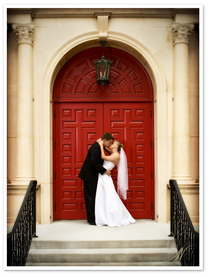 Wedding Couple Kissing by a Red Church Door